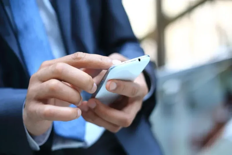 poslovni covek drzi mobilni Sajber Sfera IT Vesti, Gaming, Saveti, Vodiči